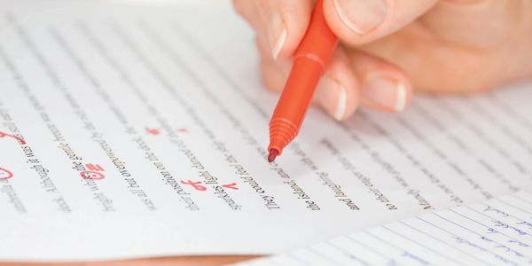 Hand marking corrections on a printed document with a red pen.