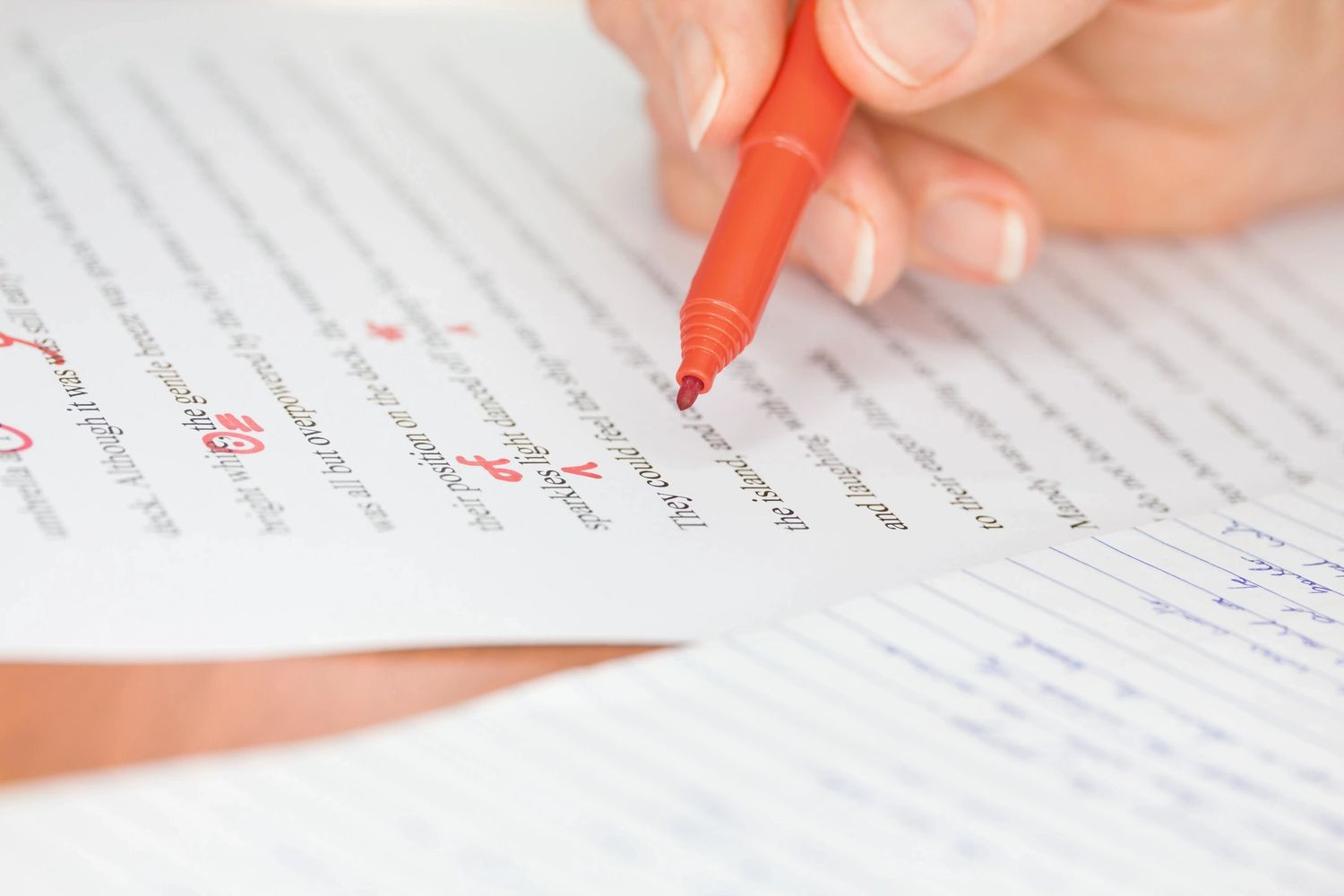 A person editing a printed document with a red pen, marking corrections.