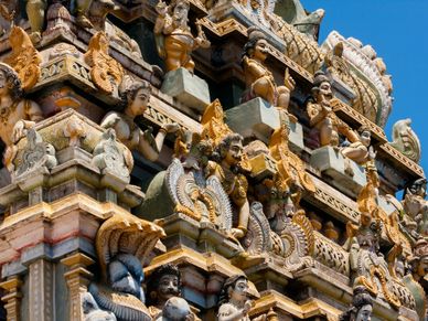 Intricate carvings on a colorful temple facade under clear blue sky.