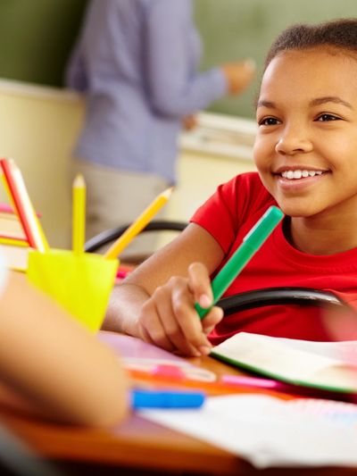 Smiling student holding a green marker in class.