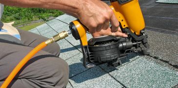 Image of nail gun nailing shingles down.