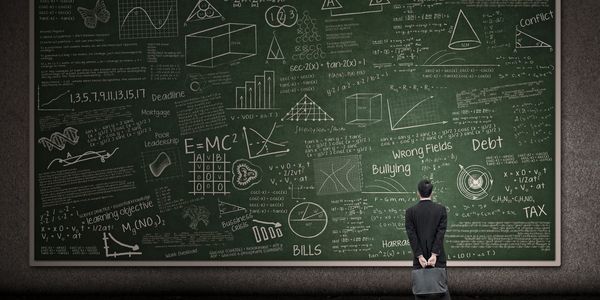 A student staring at a chalk board that is filled with mathematical equations, formulas and diagrams. The student is holding a briefcase. 