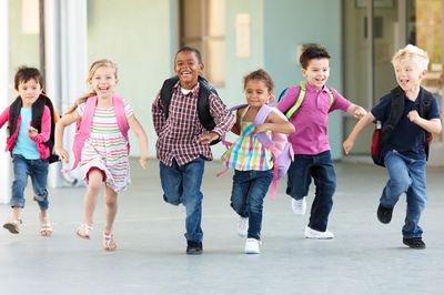 Happy children running with backpacks.