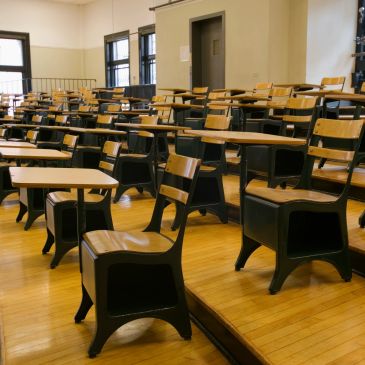Empty classroom with wooden desks and chairs.