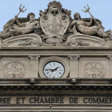 Historic building facade with clock and sculptures holding tridents.