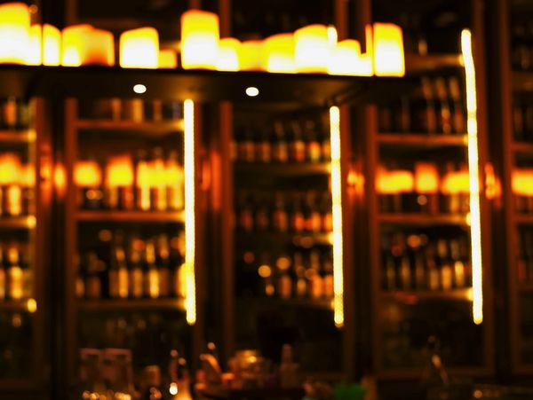 Dimly lit bar with warm, golden lighting and shelves stocked with bottles.