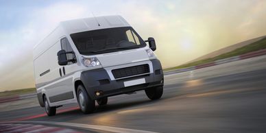 White cargo van driving on a road.
