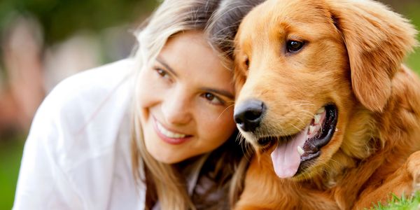 Girl and golden retriever sharing a hug