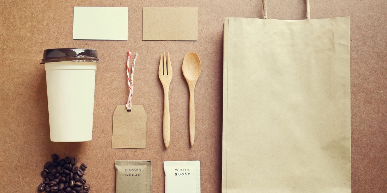 Eco-friendly coffee packaging and utensils with labels and sugar packets.