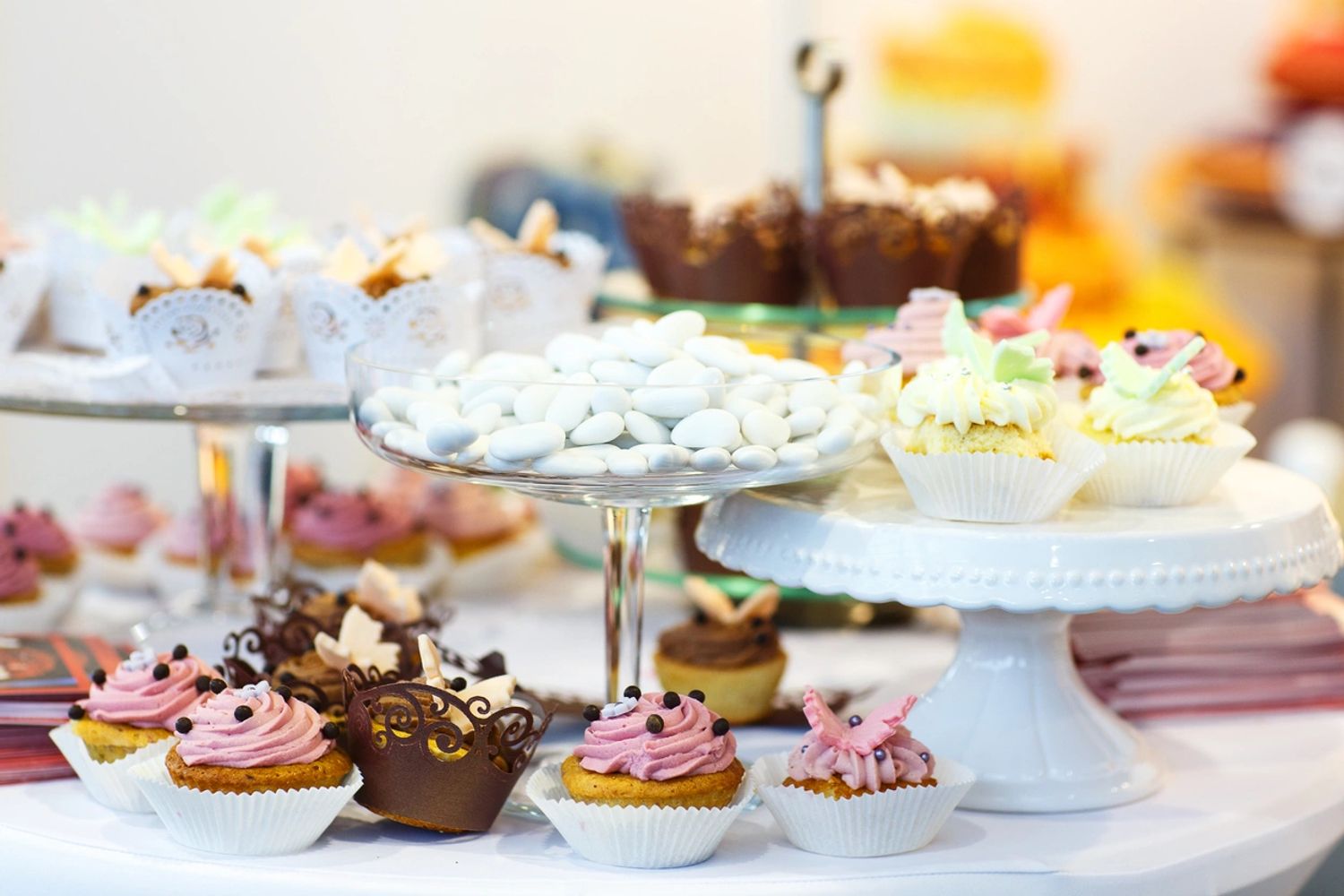 A display of assorted cupcakes and white candies at a dessert table.