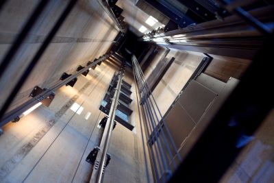 View looking up inside an elevator shaft showing cables and rails.