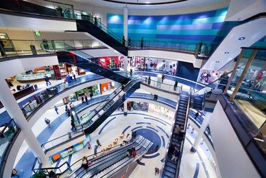 Spacious multi-level shopping mall with escalators and modern design.