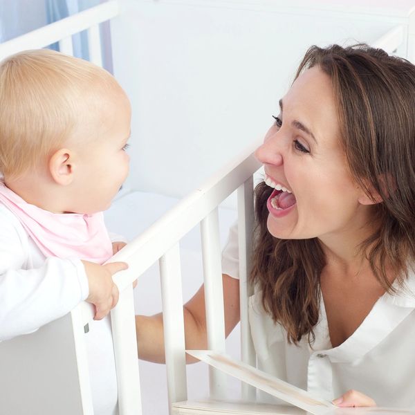 A joyful mother and baby interacting by the crib.