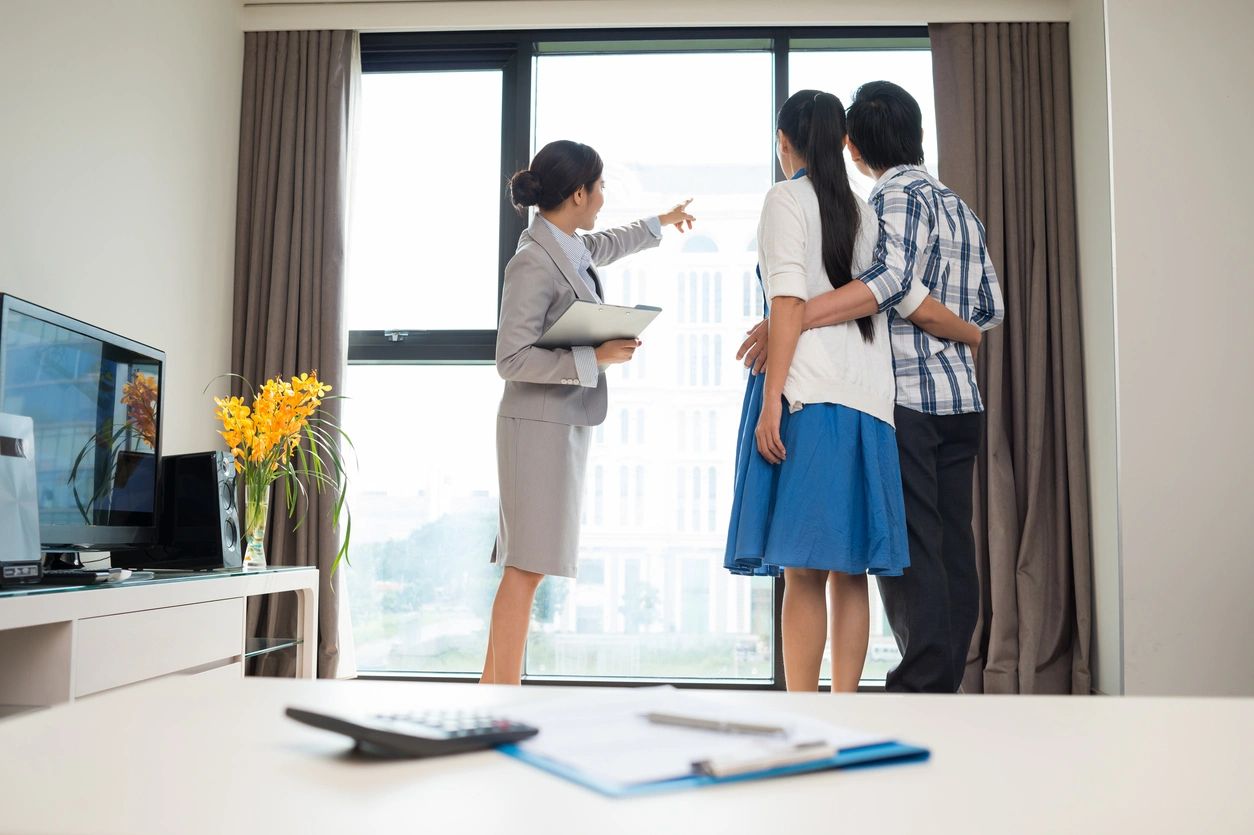 Real estate agent showing a young couple a view from an apartment window.