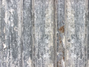 Close-up of a weathered corrugated metal surface with peeling paint.