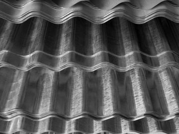 Black and white photo of corrugated metal sheets with shadows and highlights.