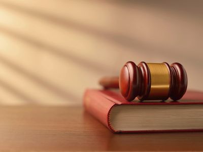 A judge's gavel resting on a thick book on a wooden surface.