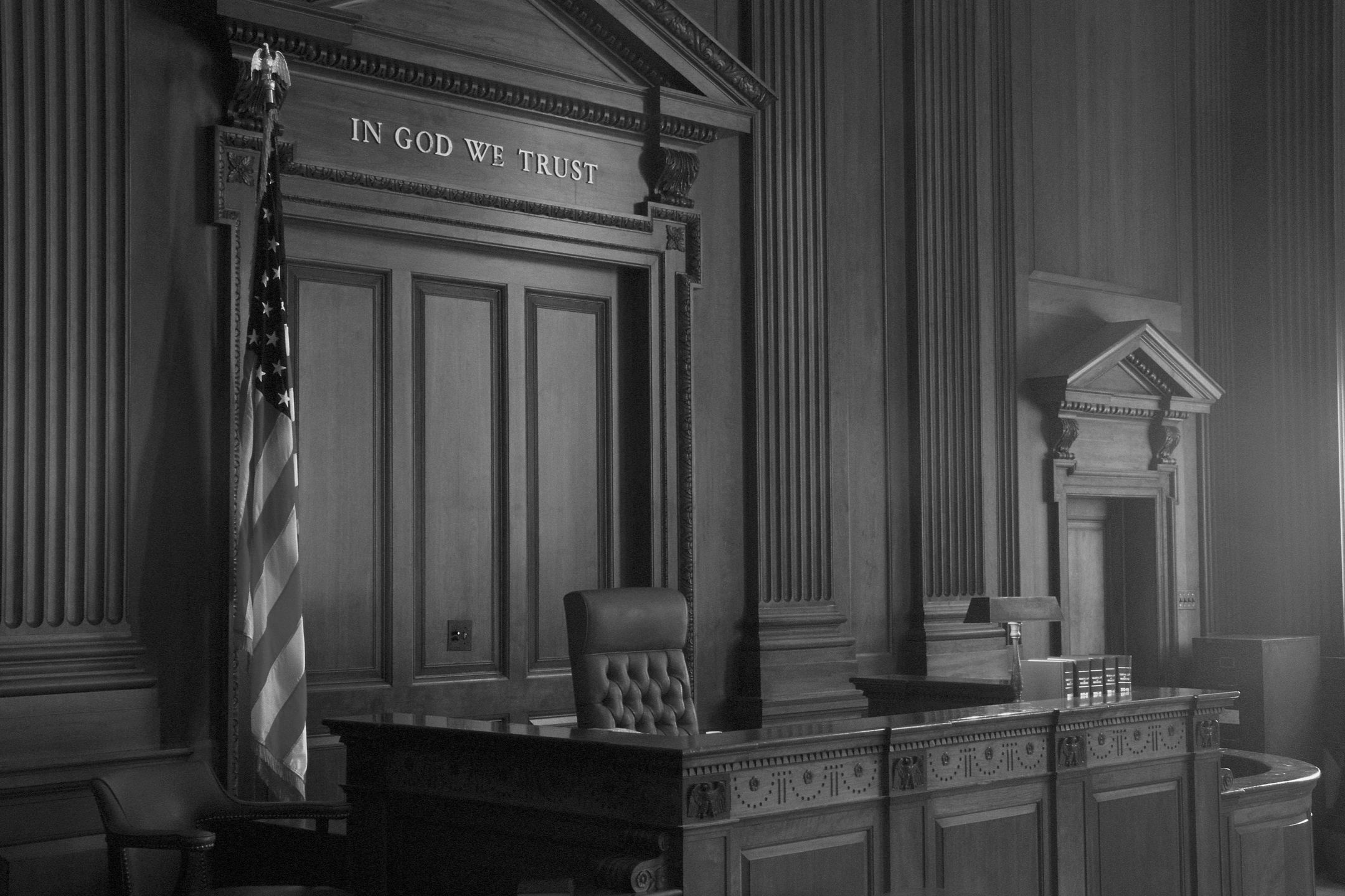 Empty courtroom with wooden decor and American flag.