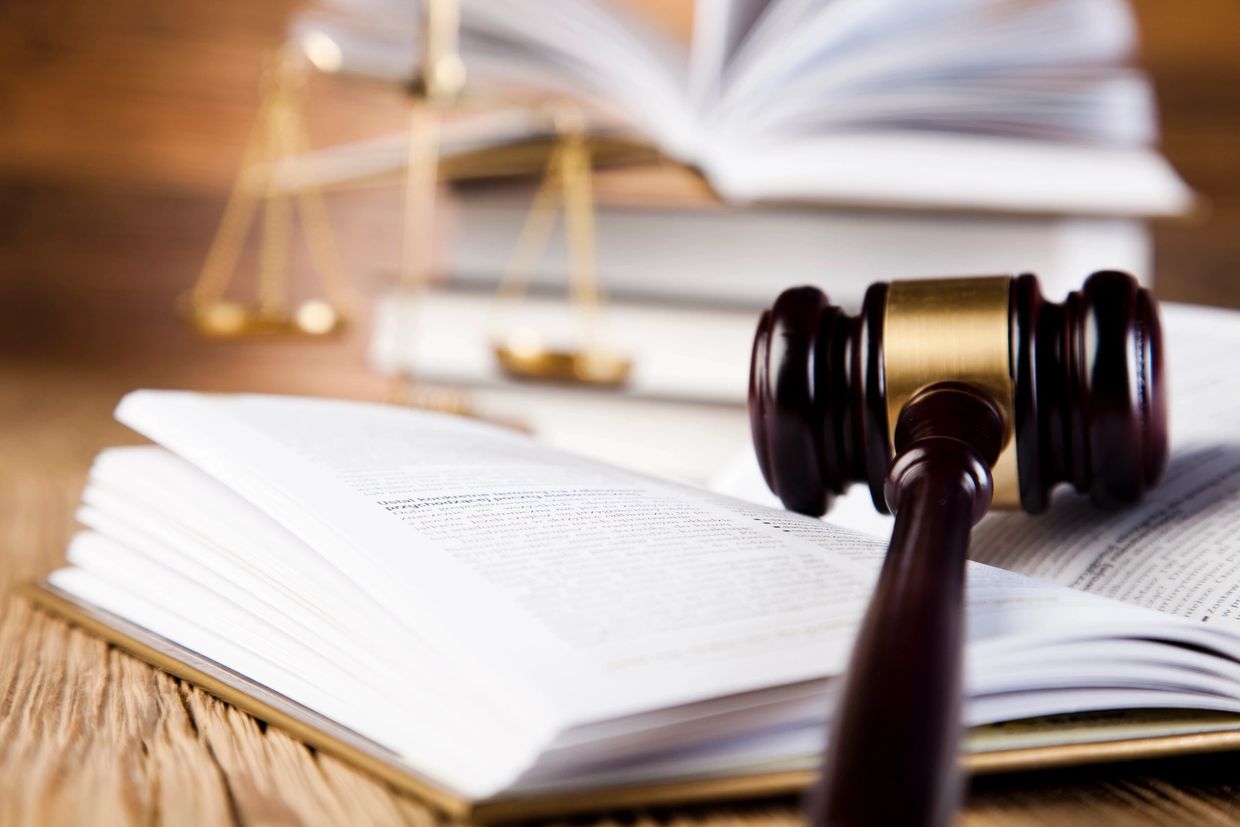Gavel and open law books with scales of justice in the background.