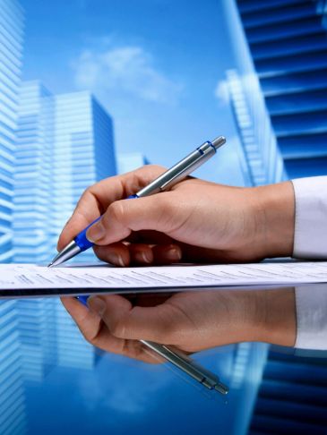 Hand signing a document with cityscape reflection.