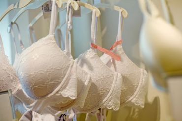 White lace bras hanging on display hangers in a store.