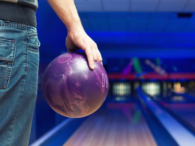 Man holding a purple bowling ball at a bowling alley.