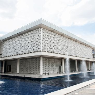 Modern building with intricate lattice facade and water fountains.