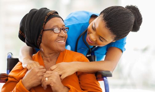 Young woman hugging elderly woman in wheelchair.