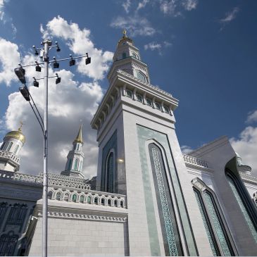 Majestic mosque tower with ornate architectural details under a bright blue sky.