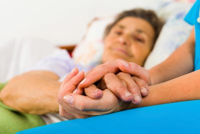 Image of elderly female holding hands with a carer