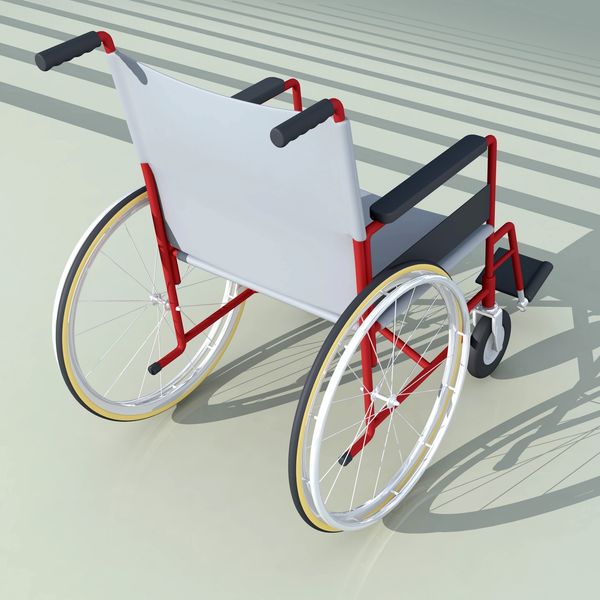 Red and white wheelchair casting shadows on a light surface.