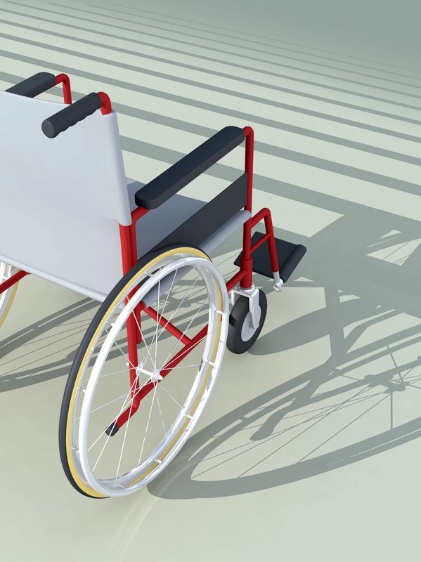 A red and white wheelchair casting a shadow on a striped surface.