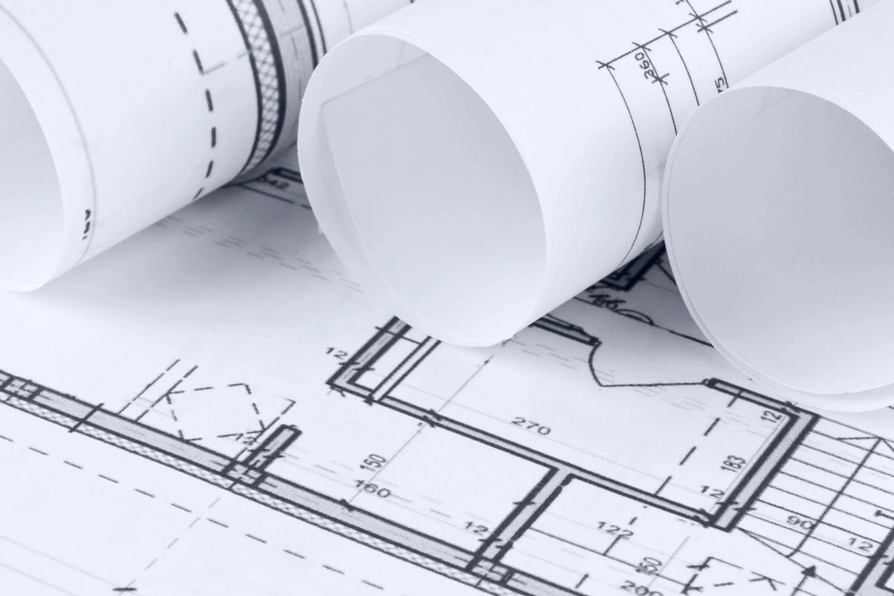 Rolled architectural blueprints resting on a detailed floor plan.
