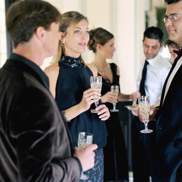 People in formal attire enjoying drinks and conversation at a social event.