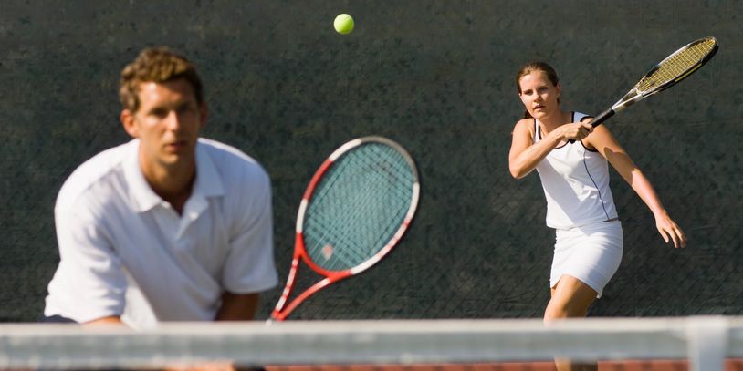 Two people playing tennis on an outdoor court