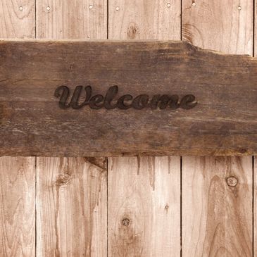 Wooden welcome sign on a wooden surface.