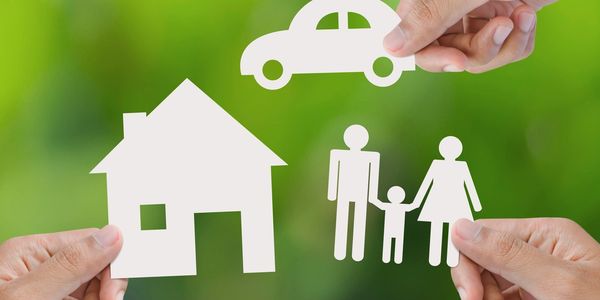 Hands holding paper cutouts of a house, family, and car against a green background.
