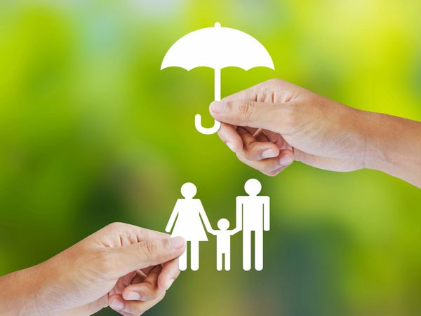 Hands holding paper cutouts of a family and umbrella symbolizing protection.