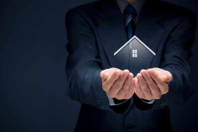 Mortgage agent holding a hologram of a home carefully in his hands