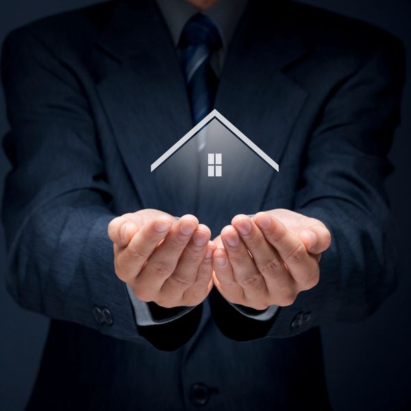 Businessman holding a glowing house icon between his hands.