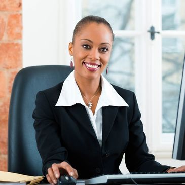 Professional woman smiling at her desk in an office setting.