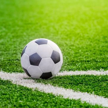 Classic black and white soccer ball on green field corner.