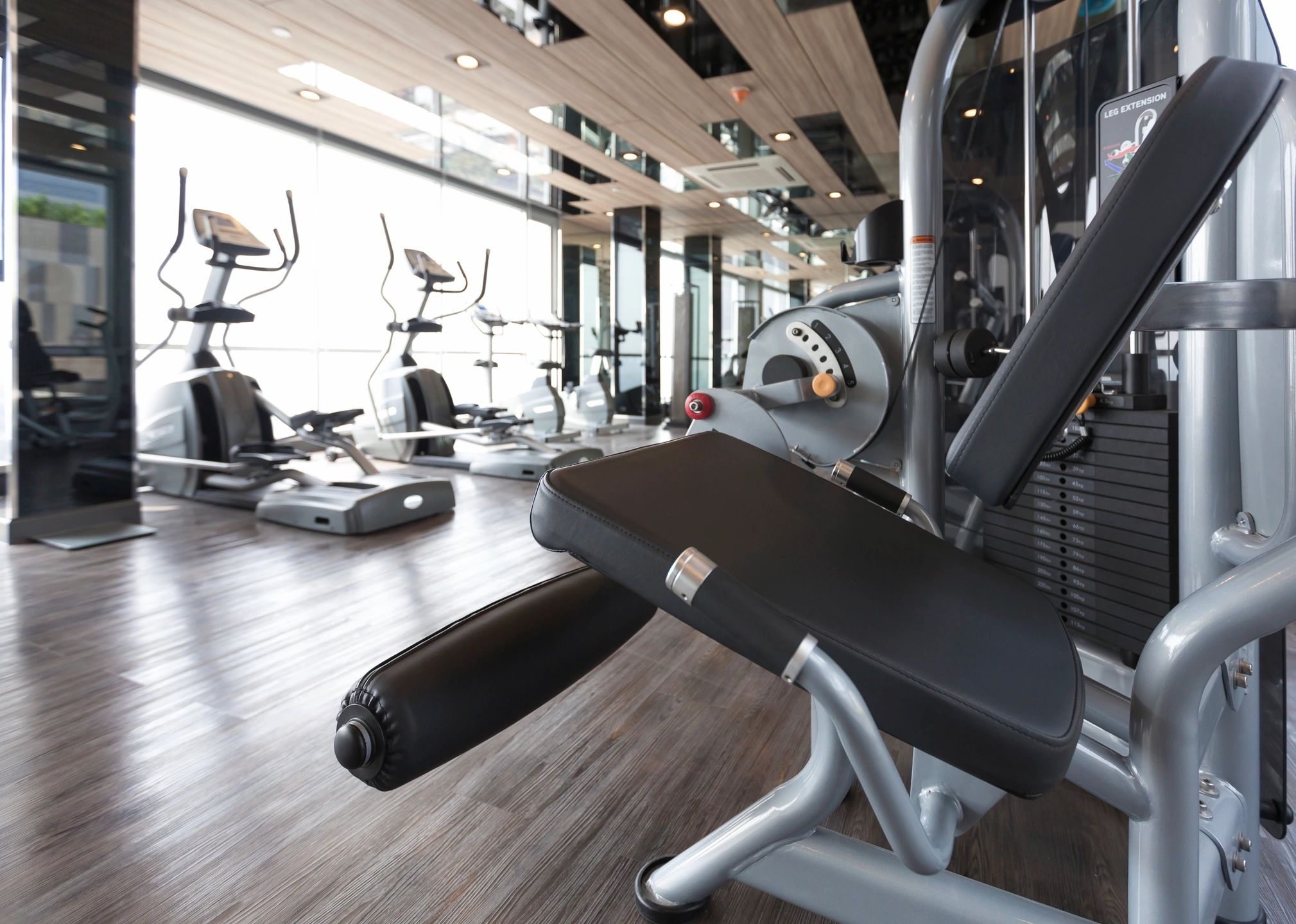 Modern gym interior with exercise machines and leg extension equipment.
