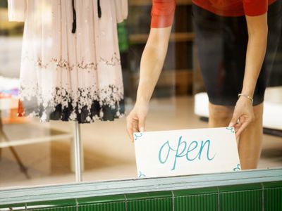 Business putting open sign in window