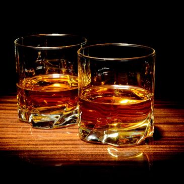 Two glasses of bourbon on a counter