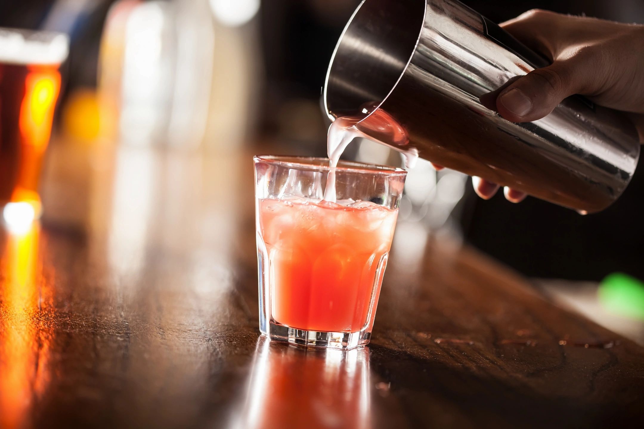 Pouring a cocktail into a glass with ice.