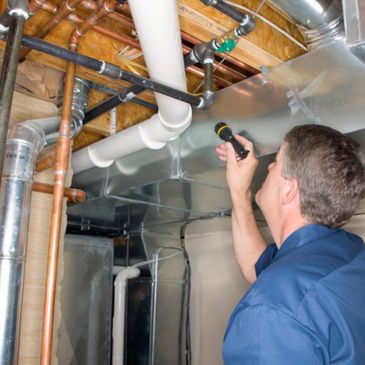 Man holding flashlight inspecting pipes