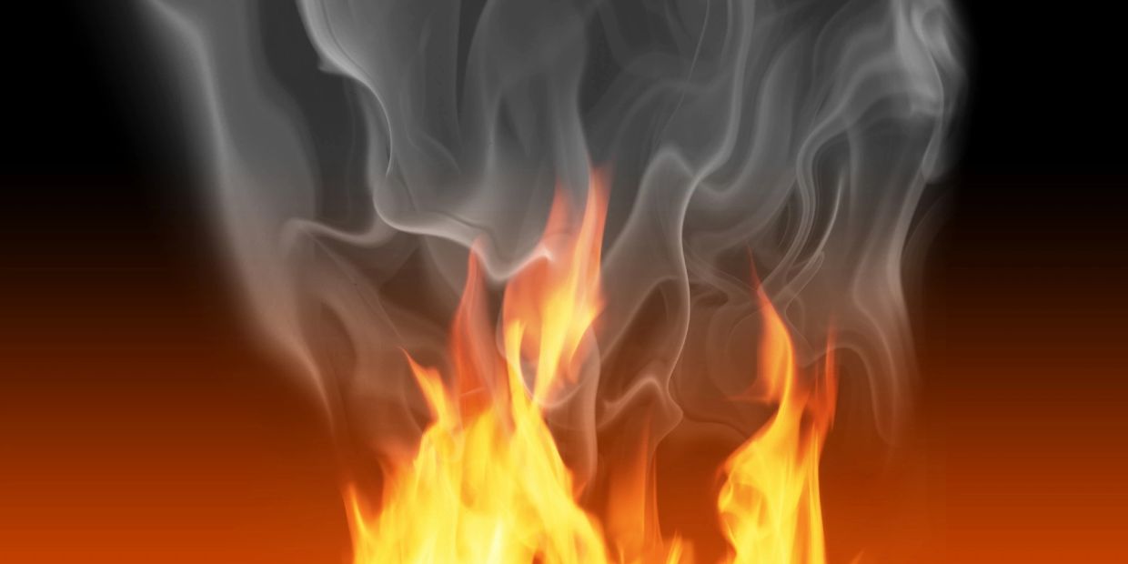 Bright orange flames with gray smoke on a black background.