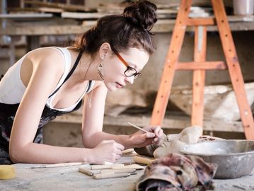 Woman sculpting clay in a workshop.