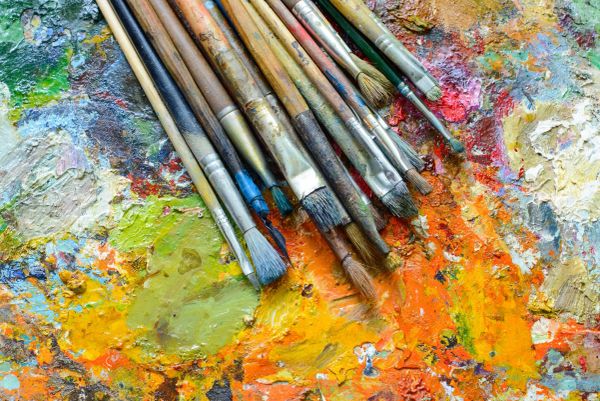 A collection of paintbrushes on a colorful, textured palette.